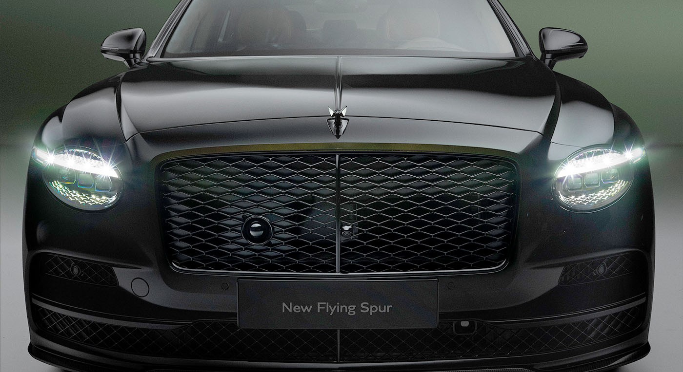 Front view of a sleek, black luxury Bentley Spur car with a prominent grille and illuminated headlights. The car exudes elegance and power, set against a dark background.
